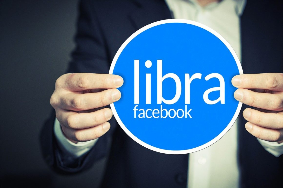 Man holds blue circular sign of Facebook's LIbra