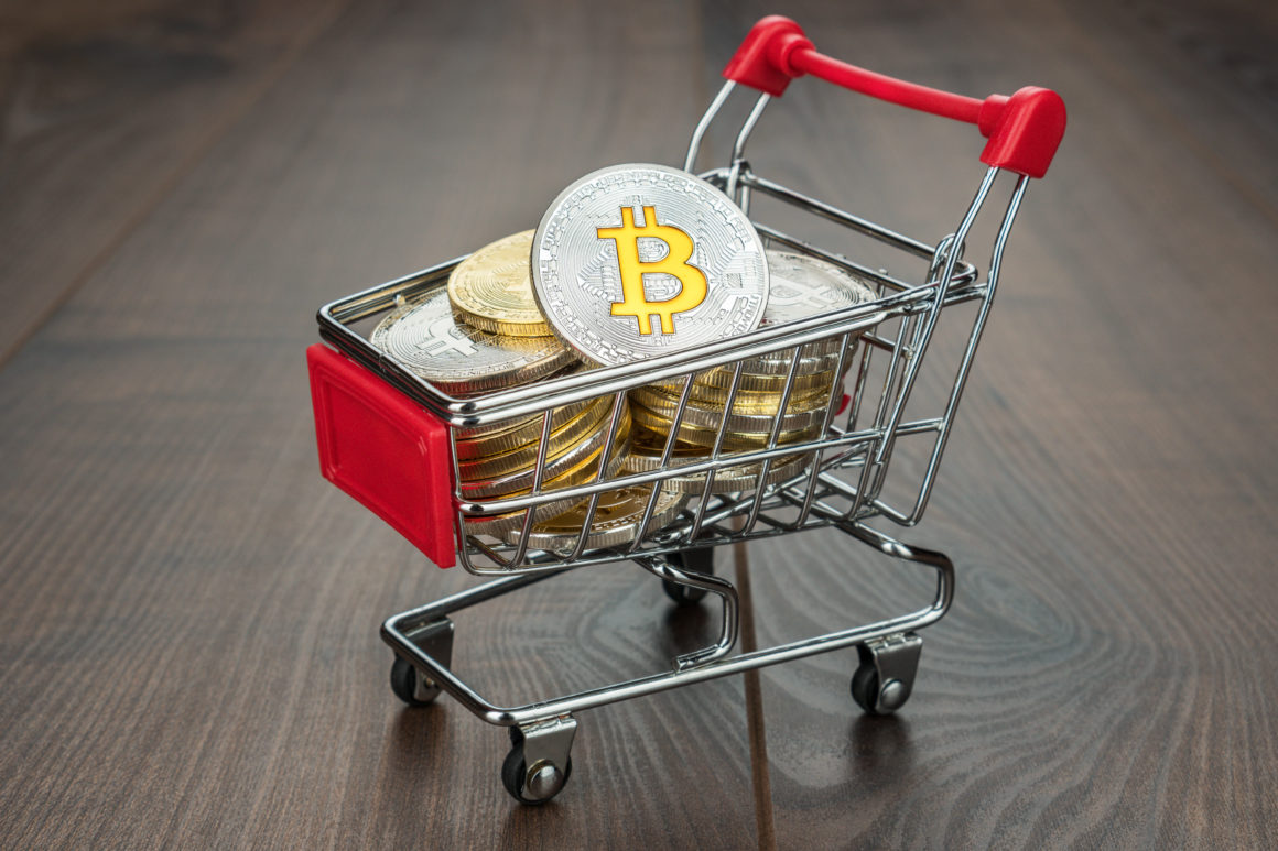 shopping trolley full of bitcoin currency concept on the wooden background