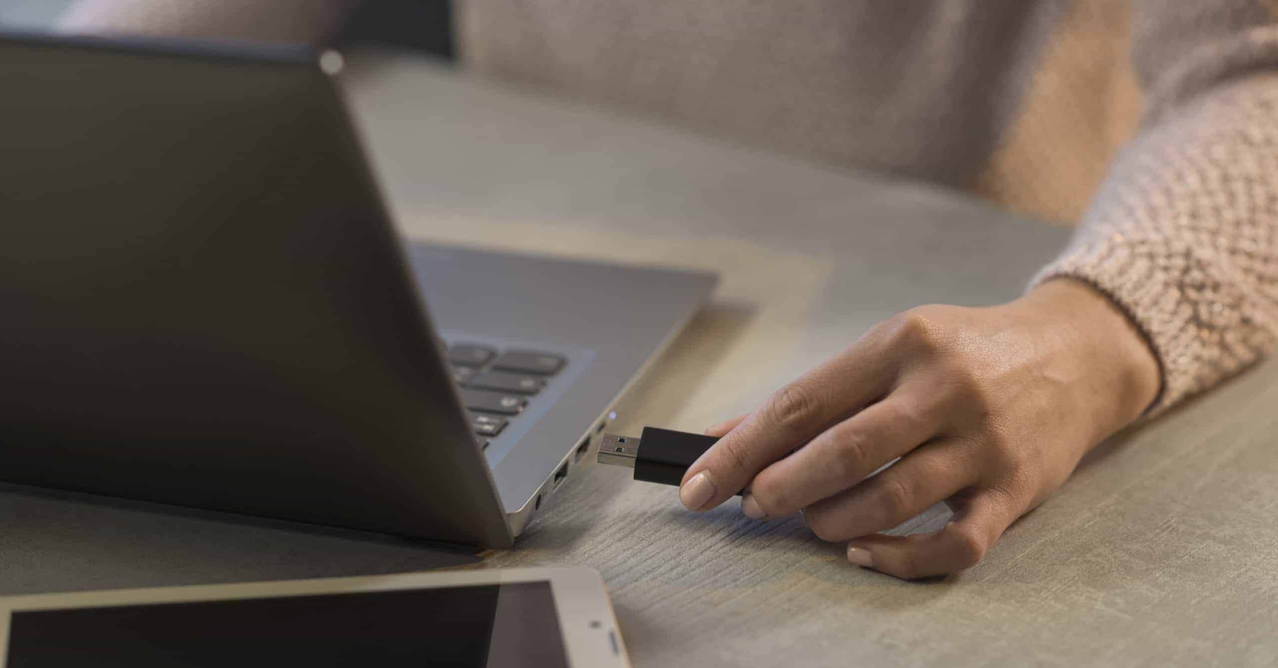 woman plugging usb drive into laptop envato elements scaled