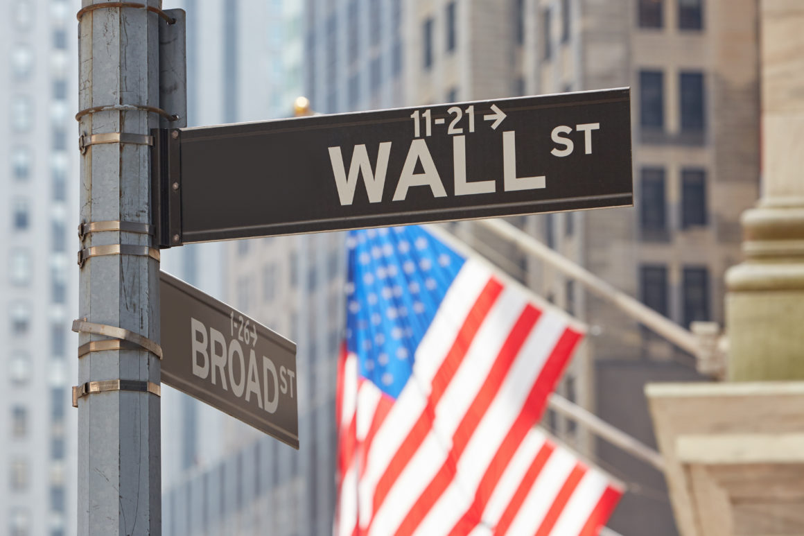 Wall Street sign near Stock Exchange with US flags, financial di