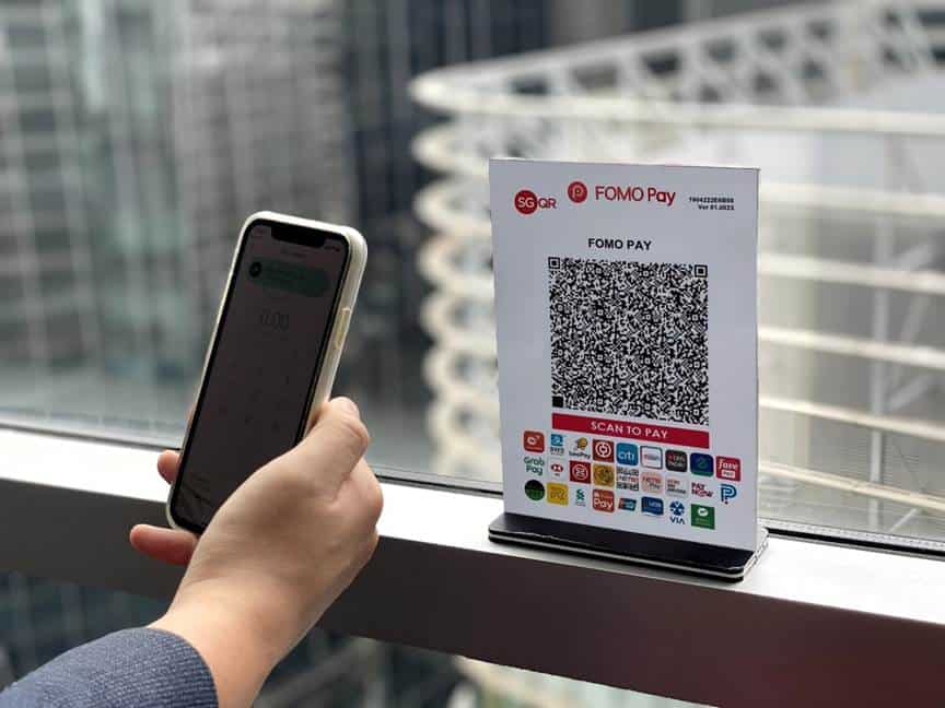 Hand holding phone scanning a FOMO Pay QR code