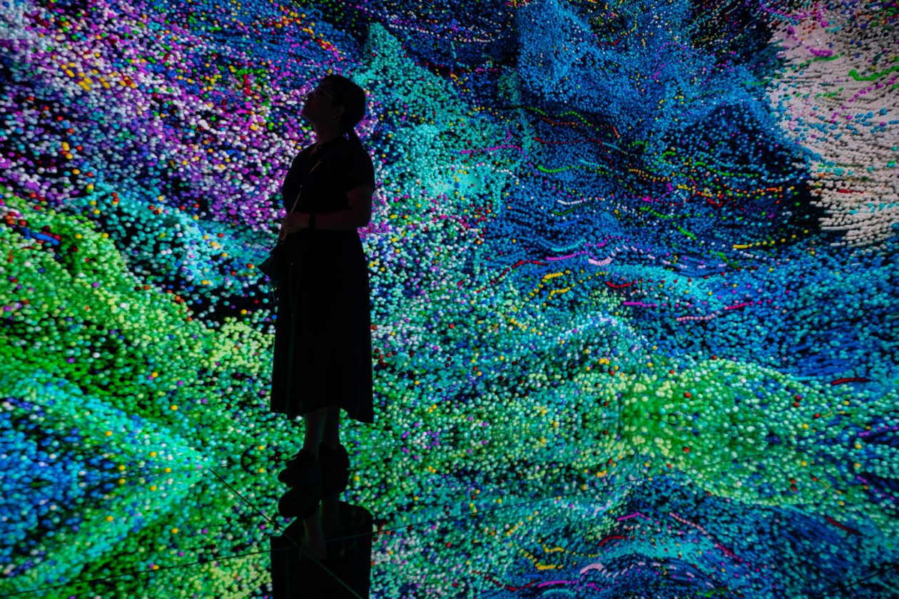 A woman standing in front of immersive digital art | Metaverse ETFs bring prominent return for investors