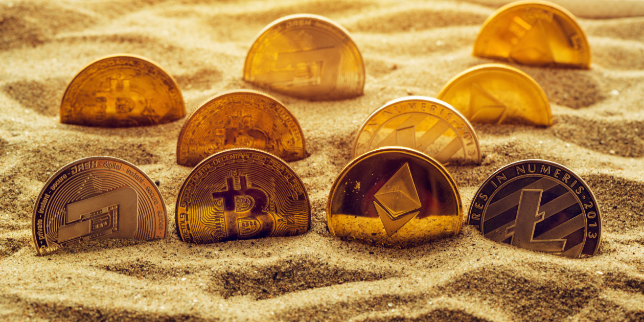Cryptocurrency coins in sand | Japan’s SBI invests in Singaporean crypto exchange Coinhako