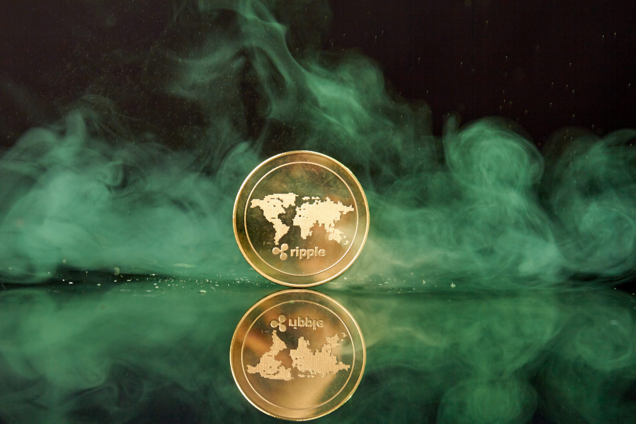 Standing golden ripple coin with smoke on reflective surface | Ripple proposes for South Korea to distinguish cryptocurrencies