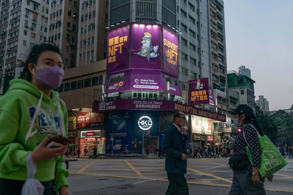 Pedestrians walk past an NFT advert in Hong Kong.