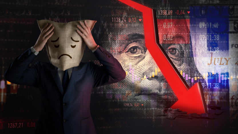 A bankrupt business man with sack with sad face drawing covering his face; stock market crash in the background