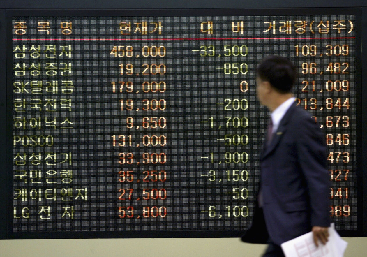 A South Korean man walks past a stock index board in Seoul, South Korea | S.Korea to set up securities market for crypto tokens | south korea crypto, south korea securities market, security token