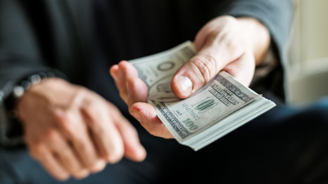 Closeup of hands holding cash, Binance and FTX lead bidding for bankrupt Voyager