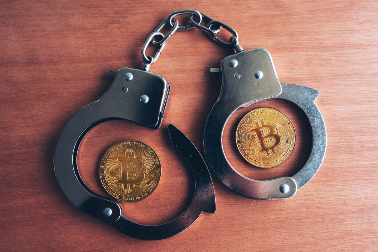 Handcuffs and bitcoins, on a wooden surface