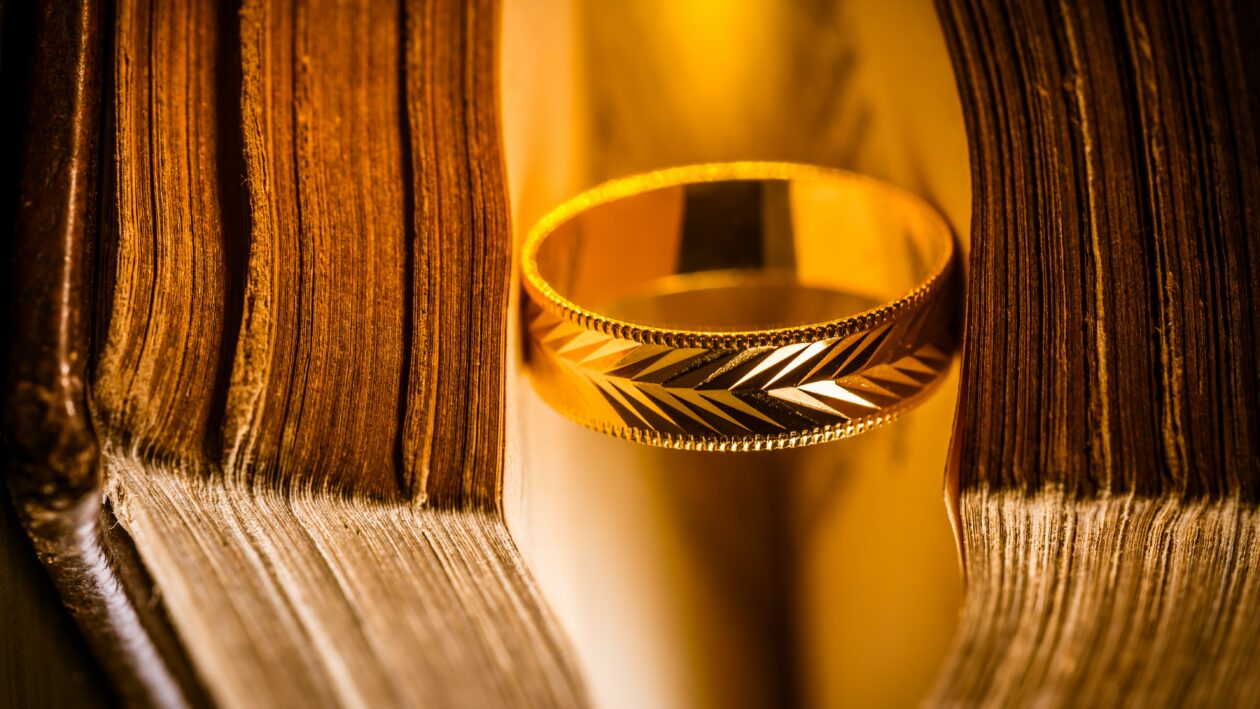 Golden ring between the pages of old book in vintage style, close up, soft focus, The Lord of the Rings, NFT
