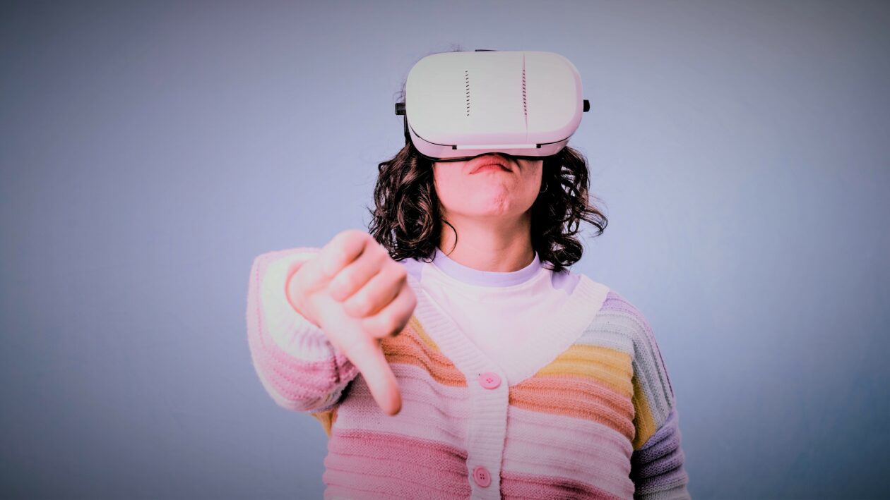 Woman showing thumb down while using VR virtual reality headset over an isolated background. Technology concept.