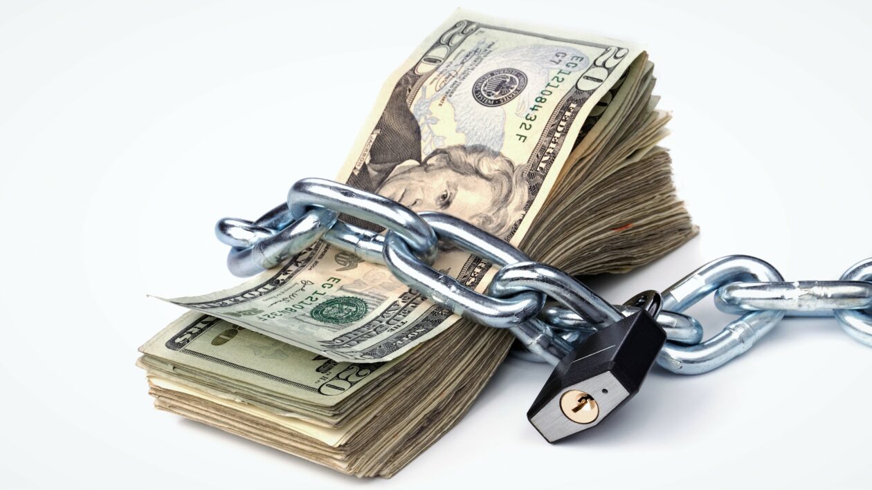A stack of currency chained together and padlocked. Used for any money inference where money is tight or protected.