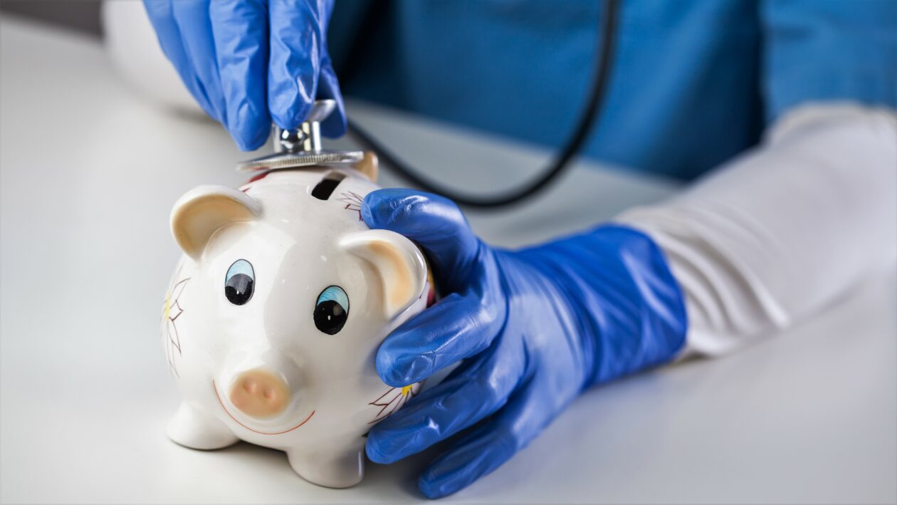 Doctor inspecting piggy bank with stethoscope, economy recession due to global COVID-19 coronavirus world pandemic outbreak,financial hardship & uncertain future,health care,life savings & insurance