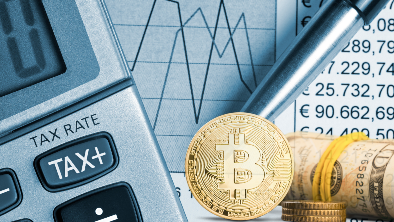 image of a calculator with focus on the TAX key, sheet of paper with numerical values, a metal pen, and Bitcoin with rolled dollar bills