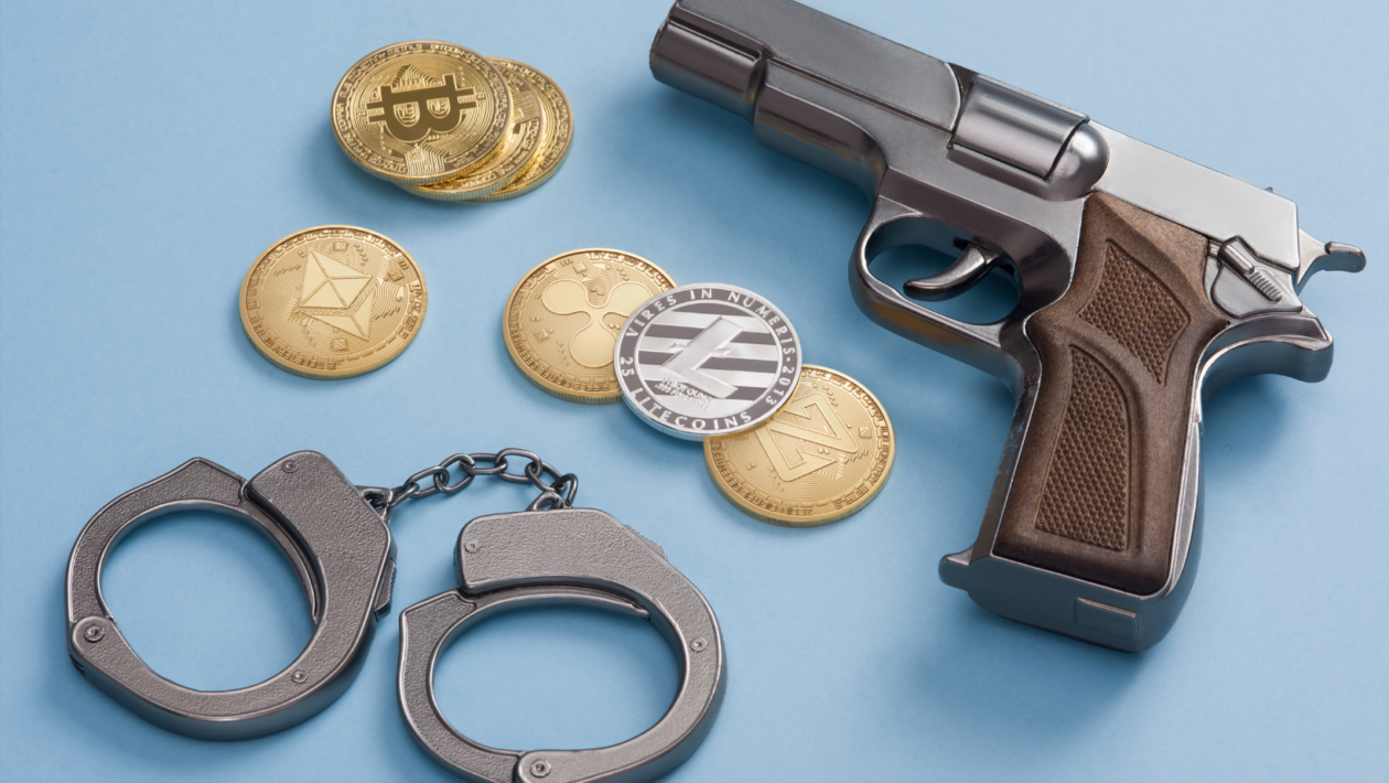 handcuffs, crypto coins, and a gun; digital crime concept