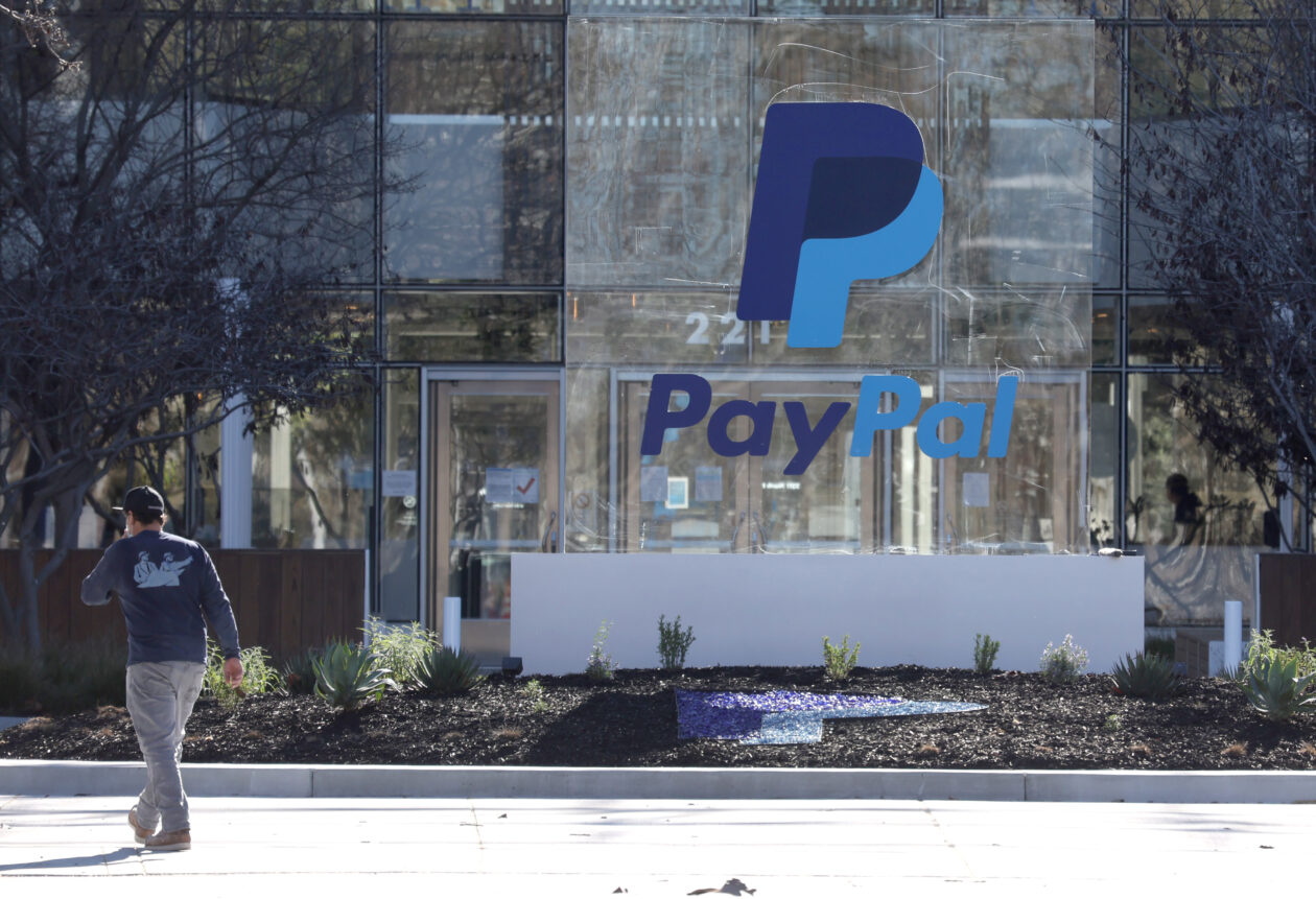 A person walking by the PayPal logo. | MetaMask partners with PayPal for Ethereum purchases through wallet