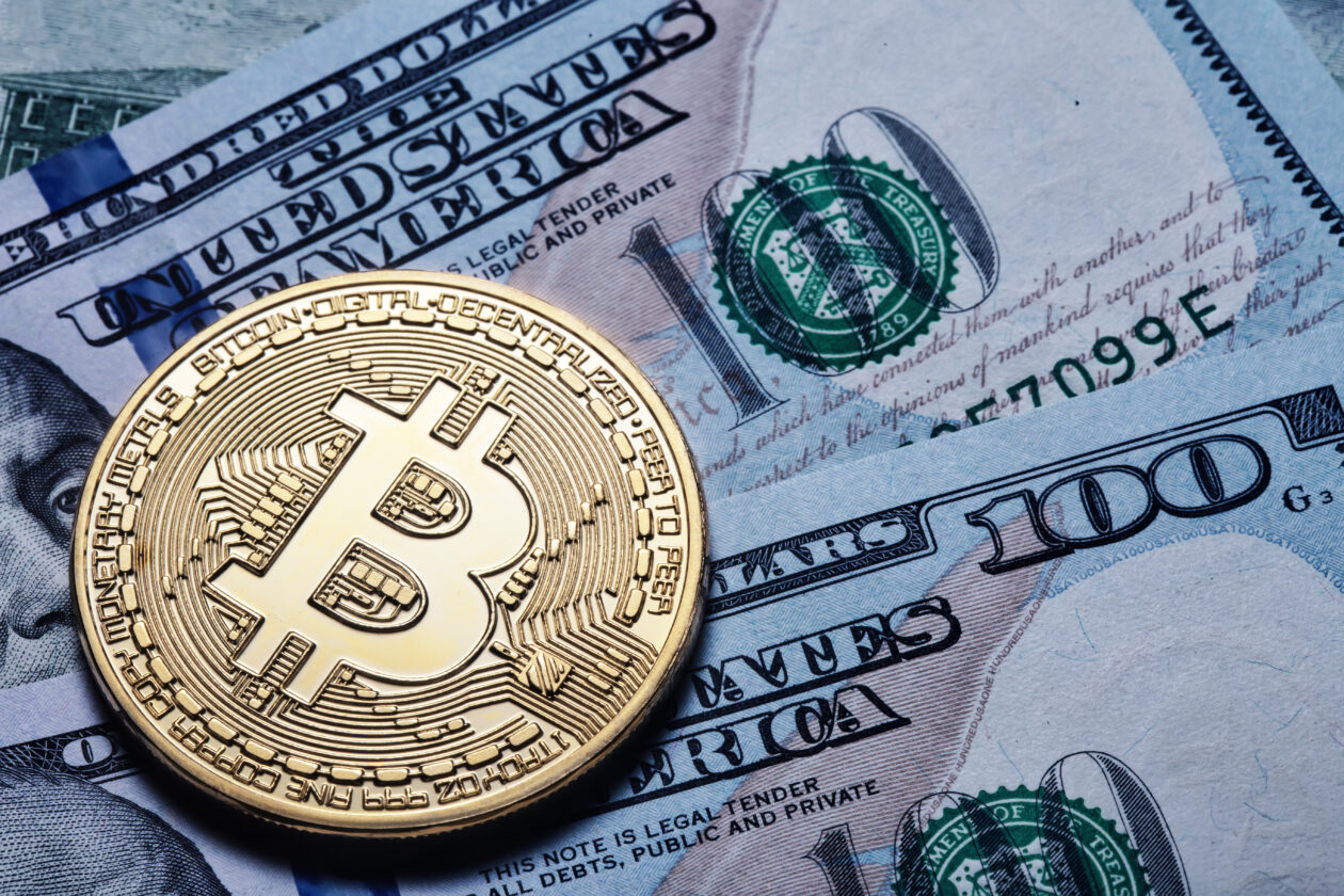 Gold bitcoin on hundred dollar bills