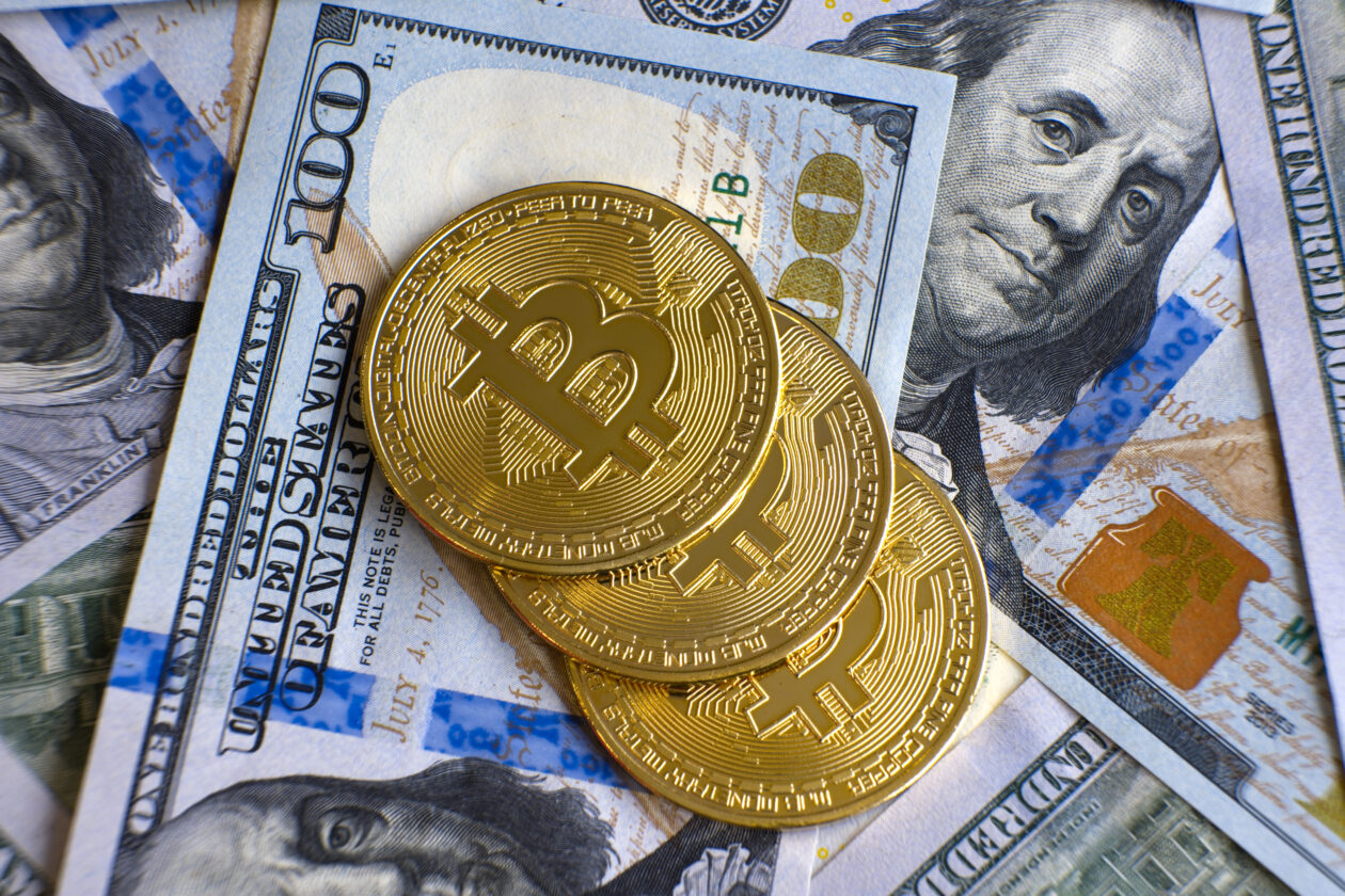 Close up of metal shiny bitcoin crypto currency coins on US dollar bills.