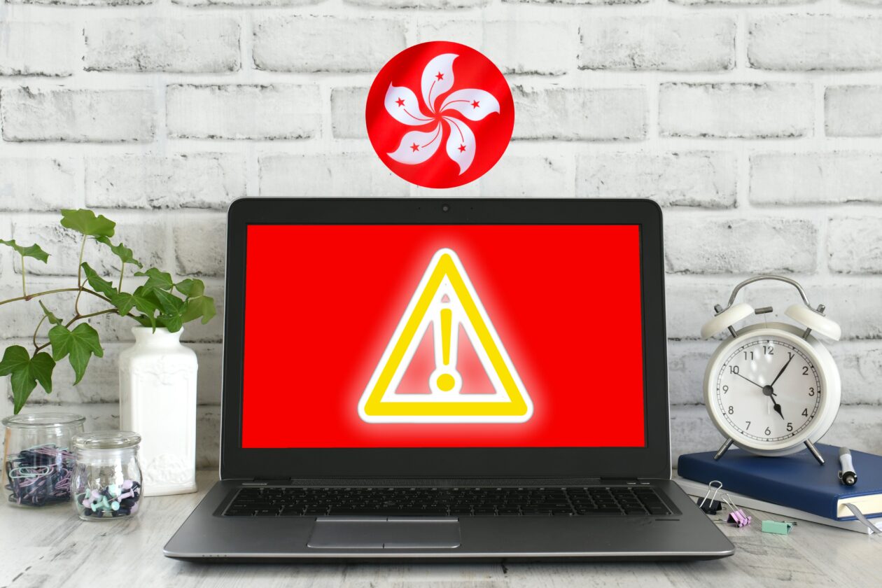 Hong Kong flag above a laptop | Hong Kong’s crypto scam losses in 2022 more than double from 2021: SCMP | Hong Kong, Cryptocurrencies, Scams, Crime, Cybersecurity