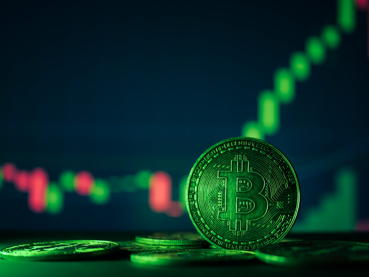 Coins with bitcoin symbol on green light and crypto stocks chart