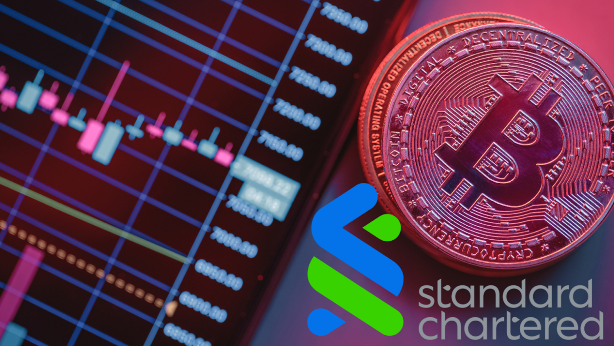 An out of focus candle graph on on a device screen with physical Bitcoin models and Standard Chartered logo layered on front. 