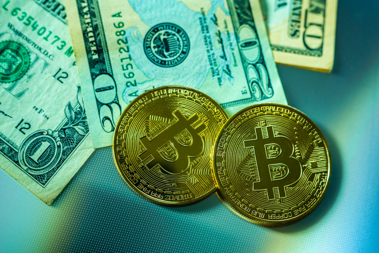 Bright bitcoin coins next to dollar bills.