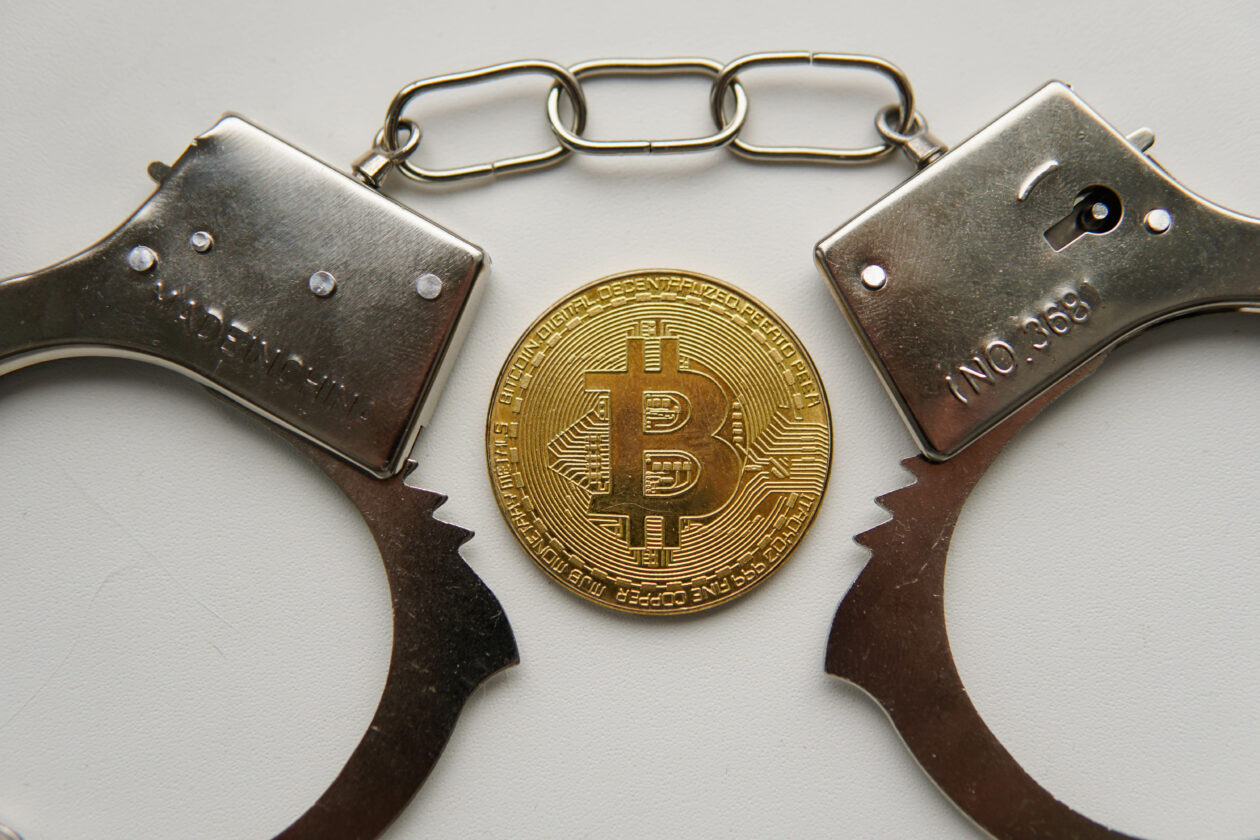 Golden bitcoin and handcuffs. Regulation and fraud of cryptocurrencies.