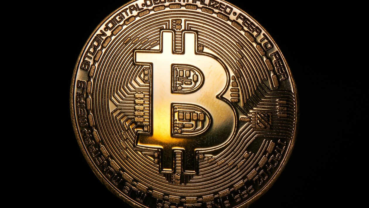 A golden Bitcoin token on a black background