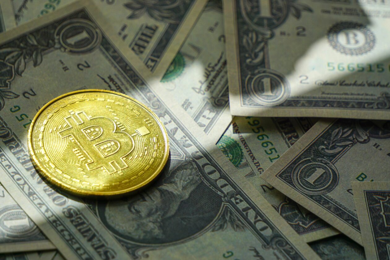 A closeup shot of a yellow bitcoin and american dollars