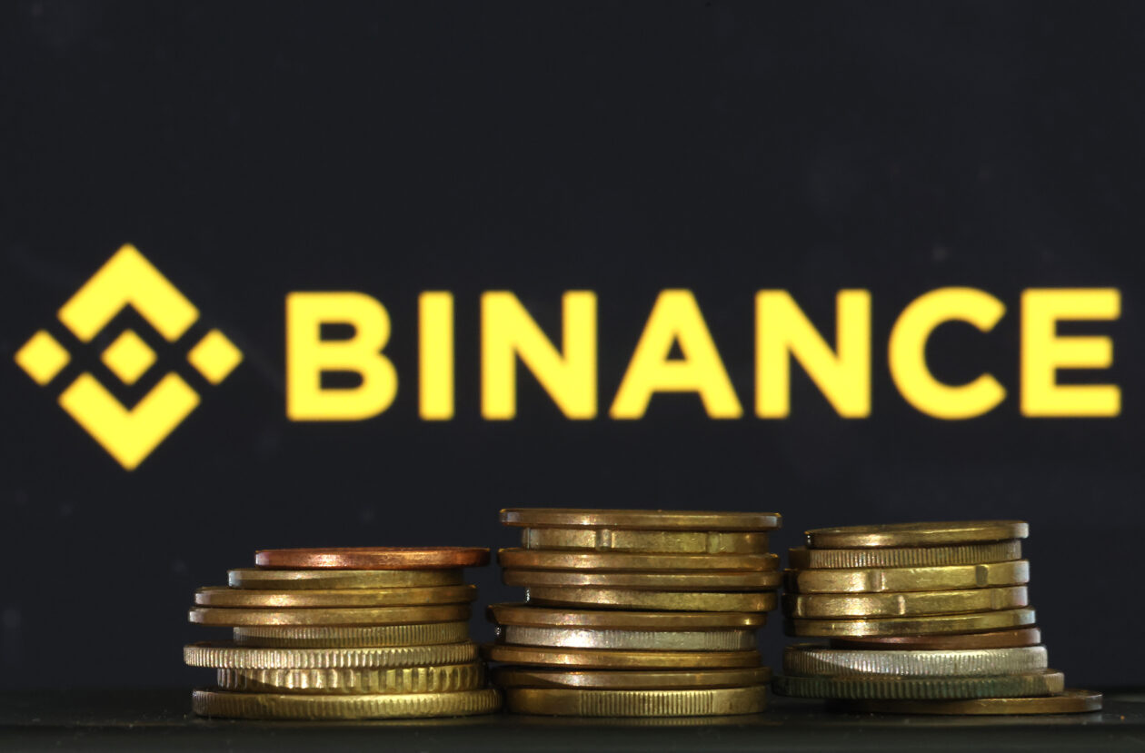 Binance logo, above three piles of golden coins