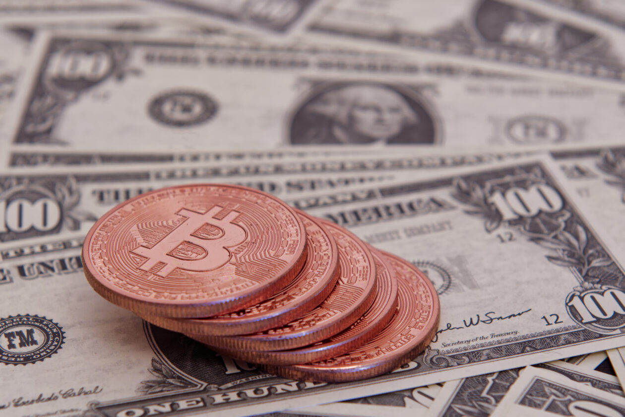 Dollar banknotes and Bitcoins on a dark wooden table