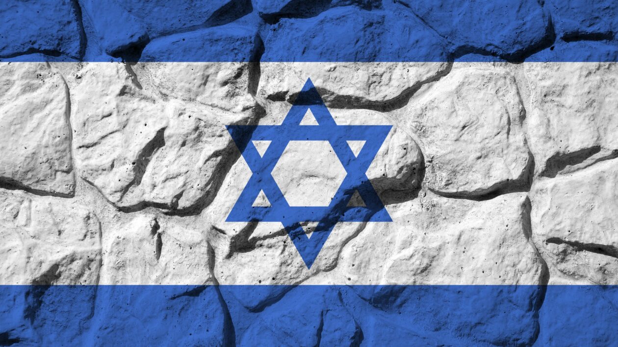 Israel flag depicted in paint colors on old stone wall close up. Textured banner on rock wall background